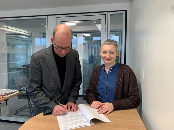 Das Bild zeigt Dr. Stefan Meyer-Ahlen, Leiter von Theologie im Fernkurs (links) und Anna Stankiewicz (rechts) bei der Unterzeichnung des Institutionellen Schutzkonzeptes.